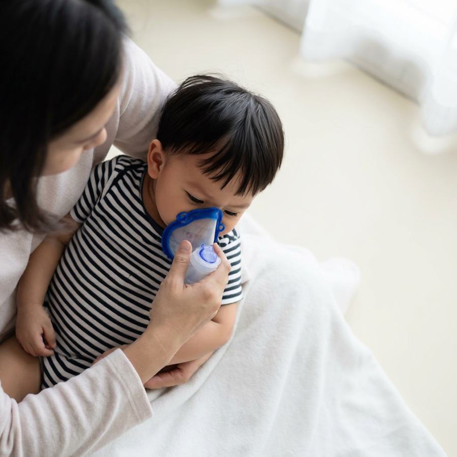 Mother helping her child use a nebuliser mask, representing children's homeopathic care